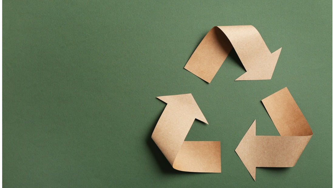Green paper background with brown paper cutouts in the shape of a recycling symbol.