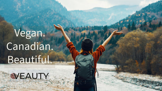 Person standing in front of a lake and mountains with arms in the air in appreciation of Canadian nature.